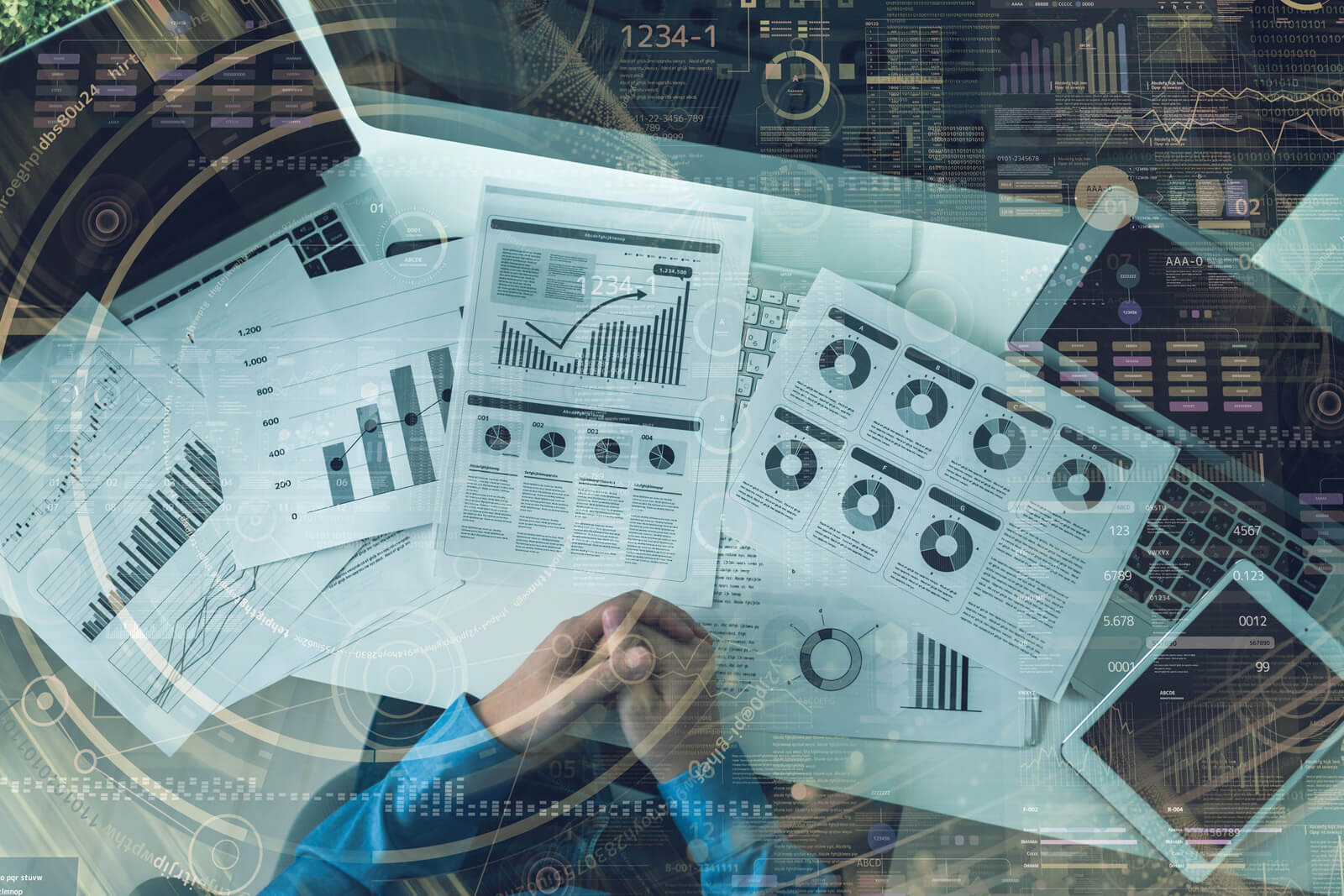 机上に並べたさまざまな書類を見ながら熟考している人